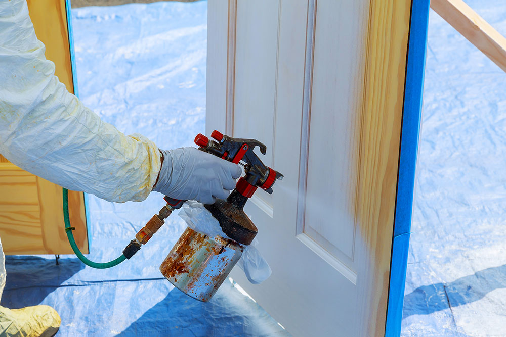 Buildnest professional applying wood stain with gloves – expert painting and carpentry services in Niagara Region