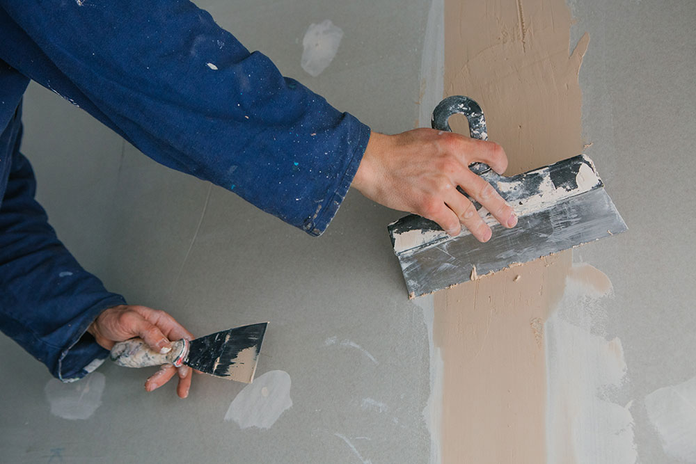 Buildnest tradesman applying joint compound with trowel – expert plastering, painting, and wall repair services in Niagara Region