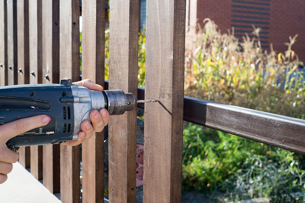 Buildnest professional using power drill on hardwood planks – expert carpentry, wood repair, and gate installation services in Niagara Region