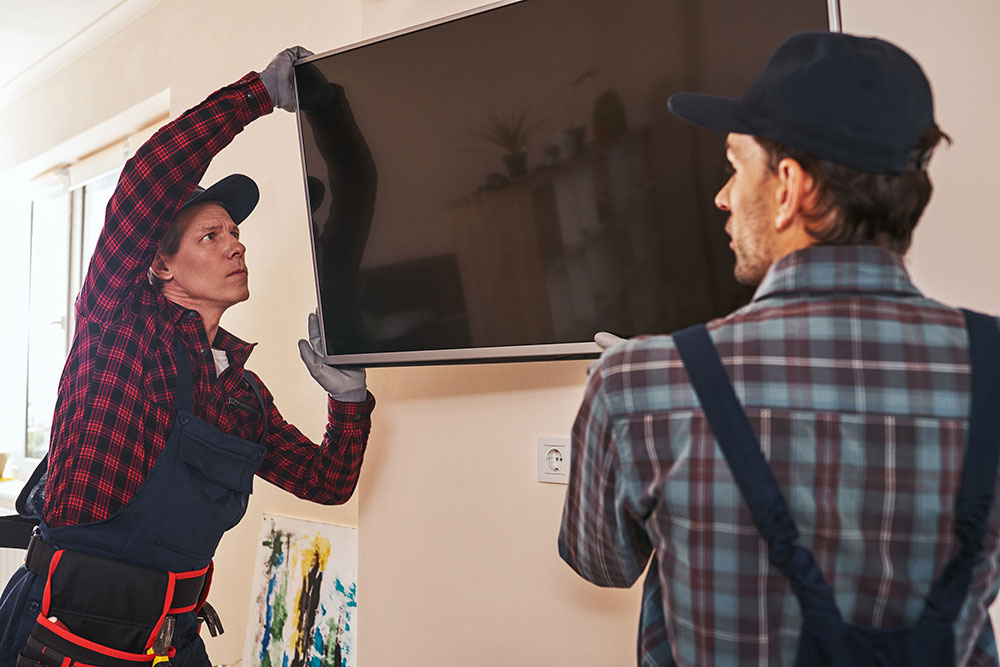 Buildnest professionals setting up flat-screen television – expert TV wall mounting and home electronics installation service in Niagara Region