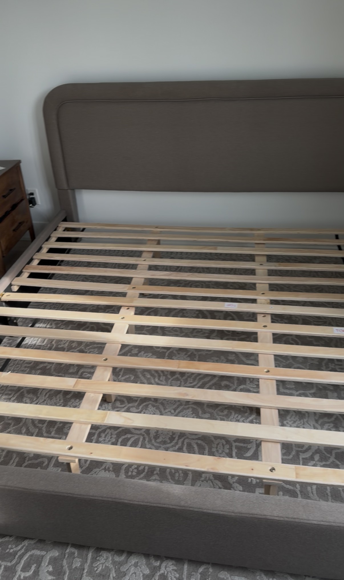 Upholstered bed frame with wooden slats being assembled by BuildNest